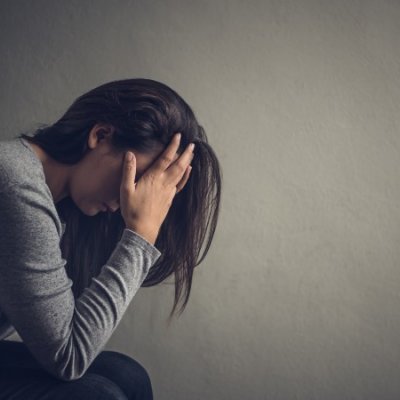 Depressed woman sitting on a chair in dark room at home. Lonly , sad, emotion concept.